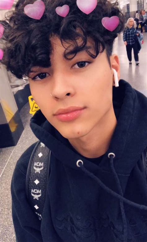 A Young Man With Curly Hair Wearing Pink Hearts On His Head And Black