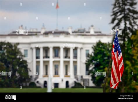 The American Flag Of A Tourist Standing In Front Of The White House In