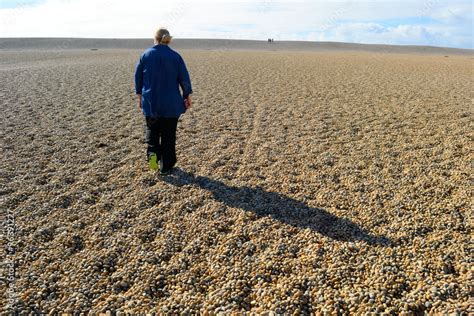 Woman walking on Chesil Beach in Dorset, England Stock Photo | Adobe Stock