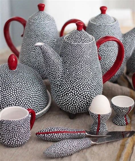 A Table Topped With Black And White Patterned Teapots