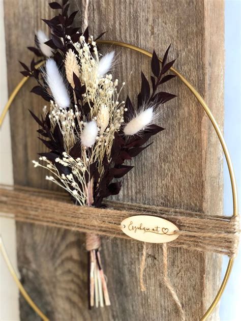 A Wooden Hoop With Some Flowers Hanging From It S Side And A Sign That