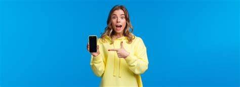 Une fille blonde joyeuse et heureuse impressionnée explique quelque chose comme pointant l écran