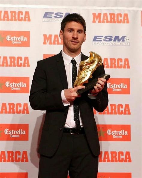 a man in a suit and tie holding a golden soccer boot at an awards ceremony