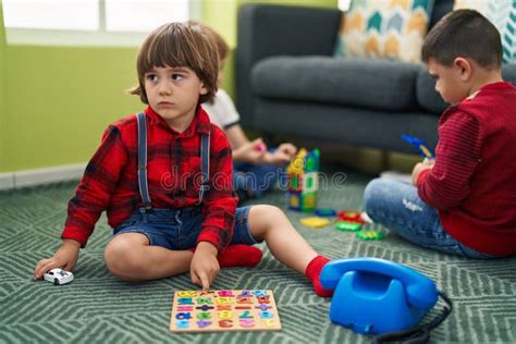 Two Kids Playing With Maths Puzzle Game Sitting On Floor At Home Stock