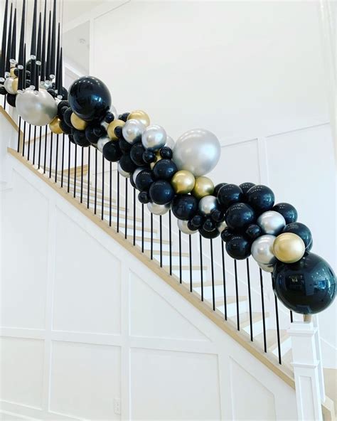 black, white and gold balloons are lined up on the stairs