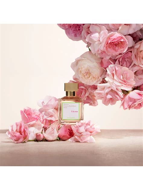 A Bottle Of Perfume Sitting Next To Pink Flowers