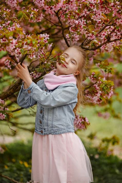 Une Fille Blonde Mignonne Sourit Sur Un Fond Des Bu Roses De Sakura Image Stock Image Du Beau