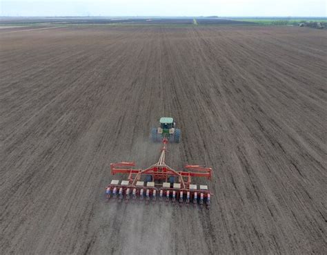 Premium Photo Sowing Of Corn Tractor With A Seeder On The Field Using