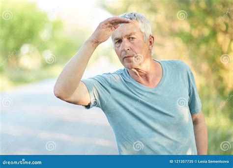 Good Looking Serious Mature Male Pensioner Keeps Hand Near Forehead Looks Into Distance Tries