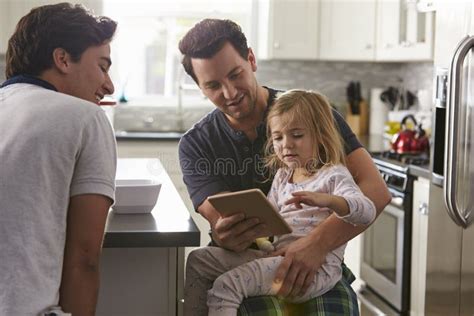 Coppie Gay Maschii Facendo Uso Della Compressa Con La Loro Figlia In Cucina Fotografia Stock