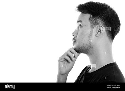 Profile View Of Young Asian Man Thinking While Looking Up Stock Photo