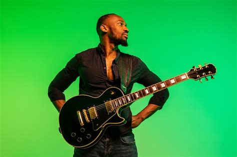 Jovem músico afro americano tocando guitarra como uma estrela do rock