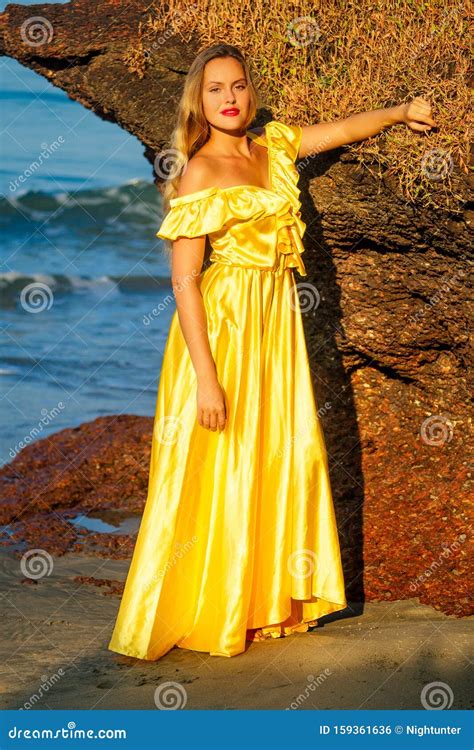 Blonde Sensuelle Aux Grosses Lèvres Rouges Se Posant Dans Une Robe De Soie Longue Jaune Vif Aux