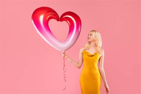 Premium Photo Joyful Blonde Woman With Twotone Heart Balloon On Pink Background