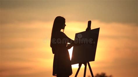 La Silueta De Una Muchacha Del Blonde Pinta Una Pintura En La Lona Con La Ayuda De Las Pinturas
