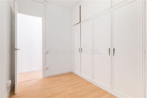 Built In Spacious Wardrobes With White Paneling And Door Open To