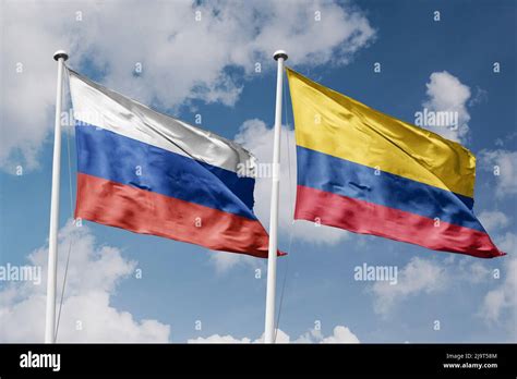 Russia And Colombia Two Flags On Flagpoles And Blue Cloudy Sky