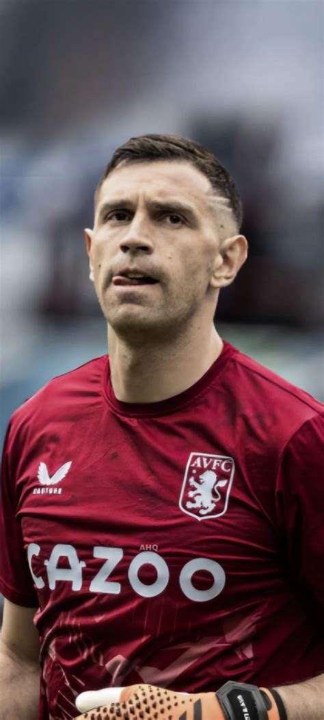 A Man Holding A Soccer Ball In His Right Hand And Wearing A Red Shirt