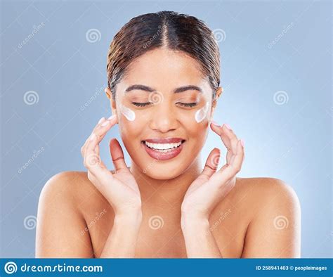 Couldnt Be Happier A Young Woman Applying Lotion To Her Face Against A