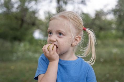 Petite Fille Blonde En T Shirt Bleu Morsure Pomme Verte Balades D