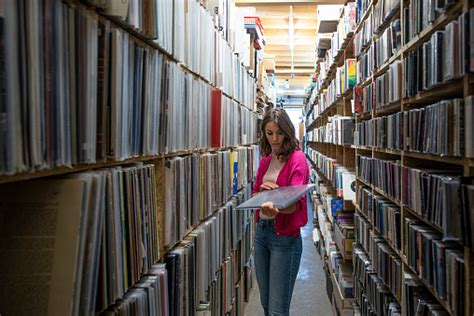 Young Female Music Fan Searching In Large Vinyl Record Collection Wide