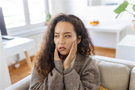 Portrait Of Unhappy Young Asian Woman Suffering From Toothache At Home