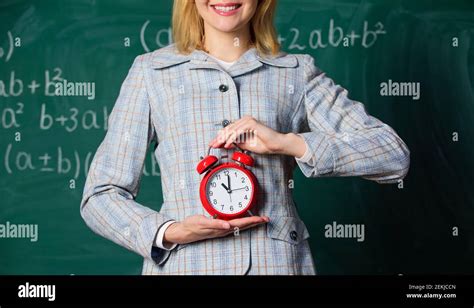 Teachers Attributes Alarm Clock In Hands Of Teacher Or Educator Classroom Chalkboard Background