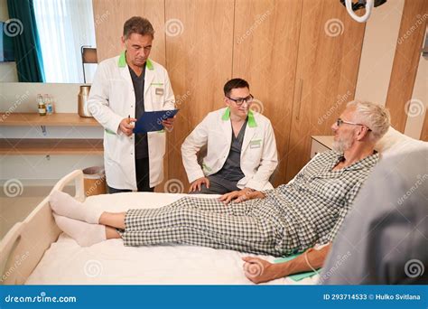 Old Man On A Hospital Bed Communicates With Clinic Staff Stock Image