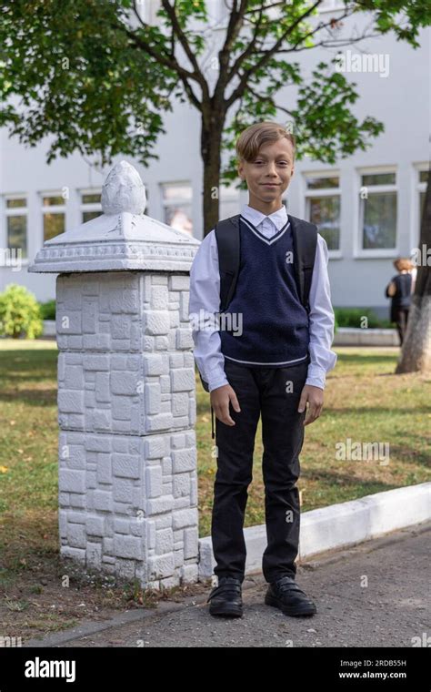 Happy boy in school uniform in a white shirt and blue vest with ...