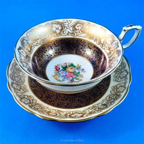 An Ornately Decorated Tea Cup And Saucer Set On A Blue Tablecloth With