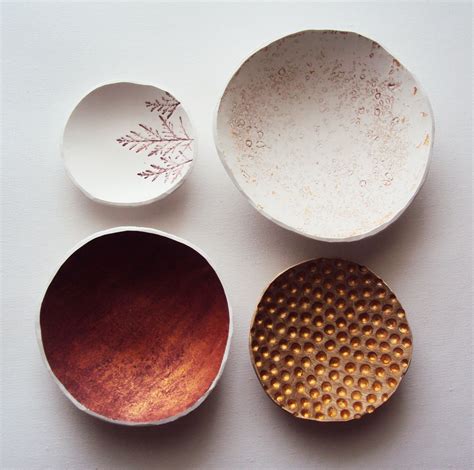 Three Bowls And One Plate Are Sitting On The Table Top With Gold Dots