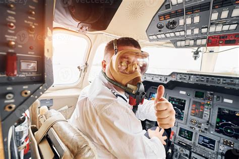 In Oxygen Mask Pilot In Formal Wear Sits In The Cockpit And Controls