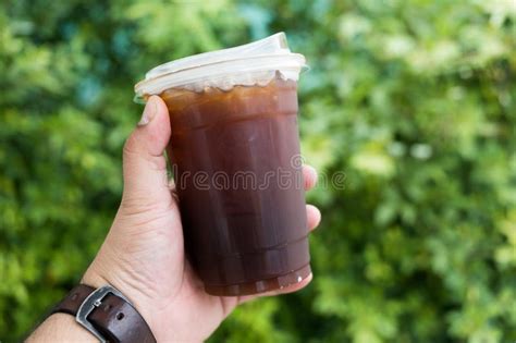 Hand Holding A Take Away Plastic Cup Of Iced Black Coffee Stock Photo