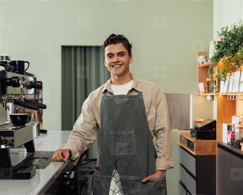 Smiling Male Barista In An Apron Looking At Camera In A Cafe Photo