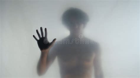 Blurred Silhouette Of A Man With A Naked Torso Behind A Frosted Curtain Or Glass The Man