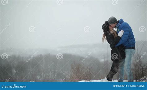 Young Happy Couple Kissing And Hugging In The Winter Snowy Forest Stock