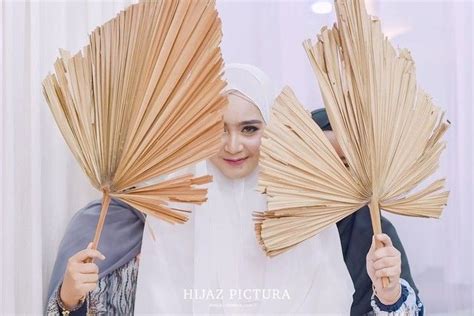 Two Women Are Holding Up Large Fan Like Objects In Front Of Their Faces