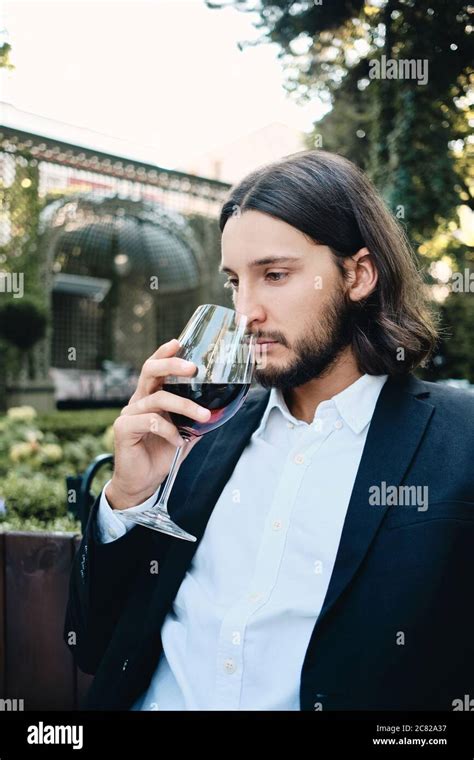 Jeune beau pensif brunette barbu homme soigneusement le vin dans le restaurant à l extérieur