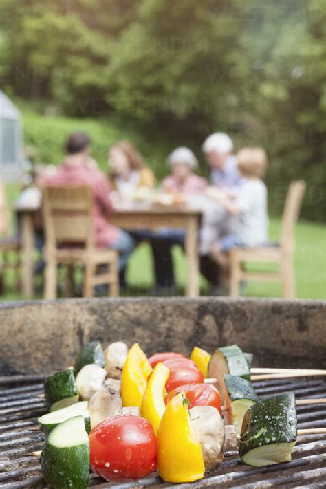 Gemüsespieße auf dem Barbecue Grill mit Familie im Hintergrund