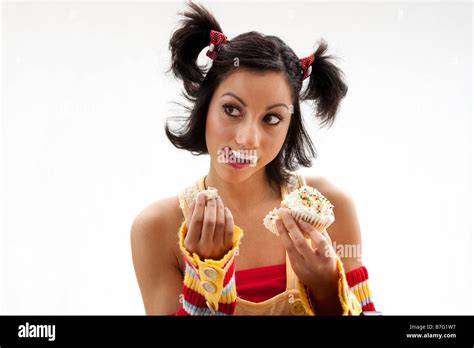 Beautiful Latina Girl Eating A Cupcake With Her Fingers And Licking Her Icing Covered Lip