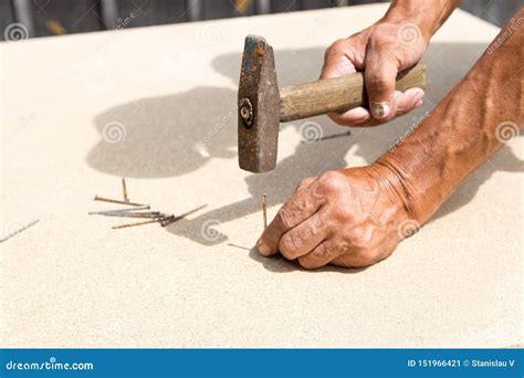 Old Hammer And Nail In The Hands Of An Elder Man Carpenter Hammers A