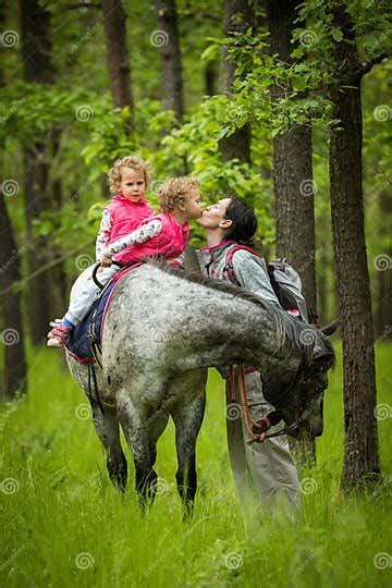 Girls Enjoying Horseback Riding In The Woods With Mother Young Pretty