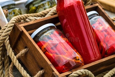 Glass Jars With Pickled Red Bell Peppers And Bottles With Tomatoes