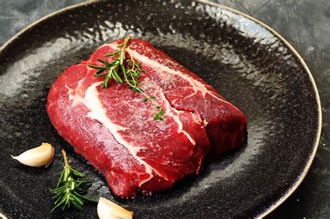 Filete De Ternera Cruda Con Romero Y Ajo En Un Plato Oscuro Foto Premium