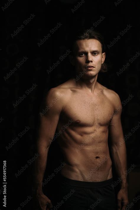 Man With An Athletic Body With A Naked Torso In The Dark A Thin Athletic Figure Of A Man