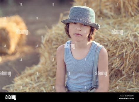 Portrait Of A Barefoot Boy In A Sleeveless Shirt And Trousers With