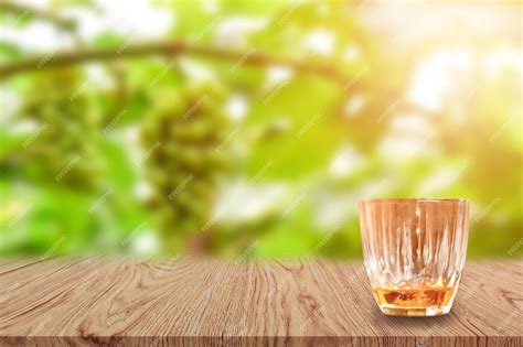 Premium Photo A Glass Of Whiskey On Wooden Table And Light Blurred Nature Background