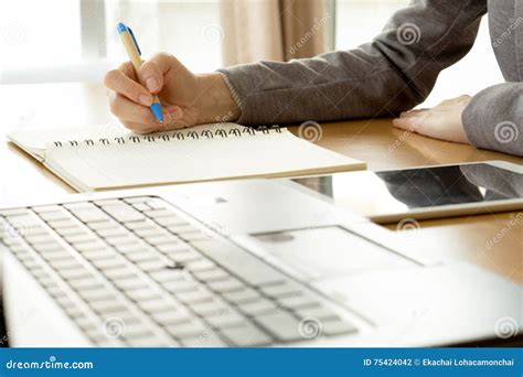 Working Woman Writing On Paper And Typing On Laptop Com Stock Photo