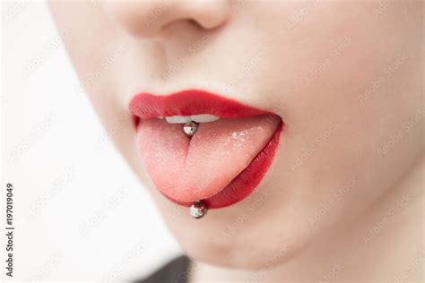 woman's mouth with red lips opened and with a piercing in a tongue ...