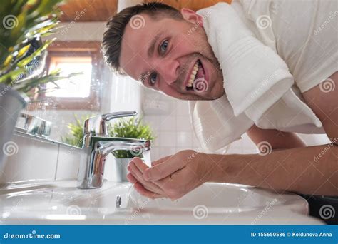 Caucasian Man Washing Face In A Wash Basin In White Washroom Stock